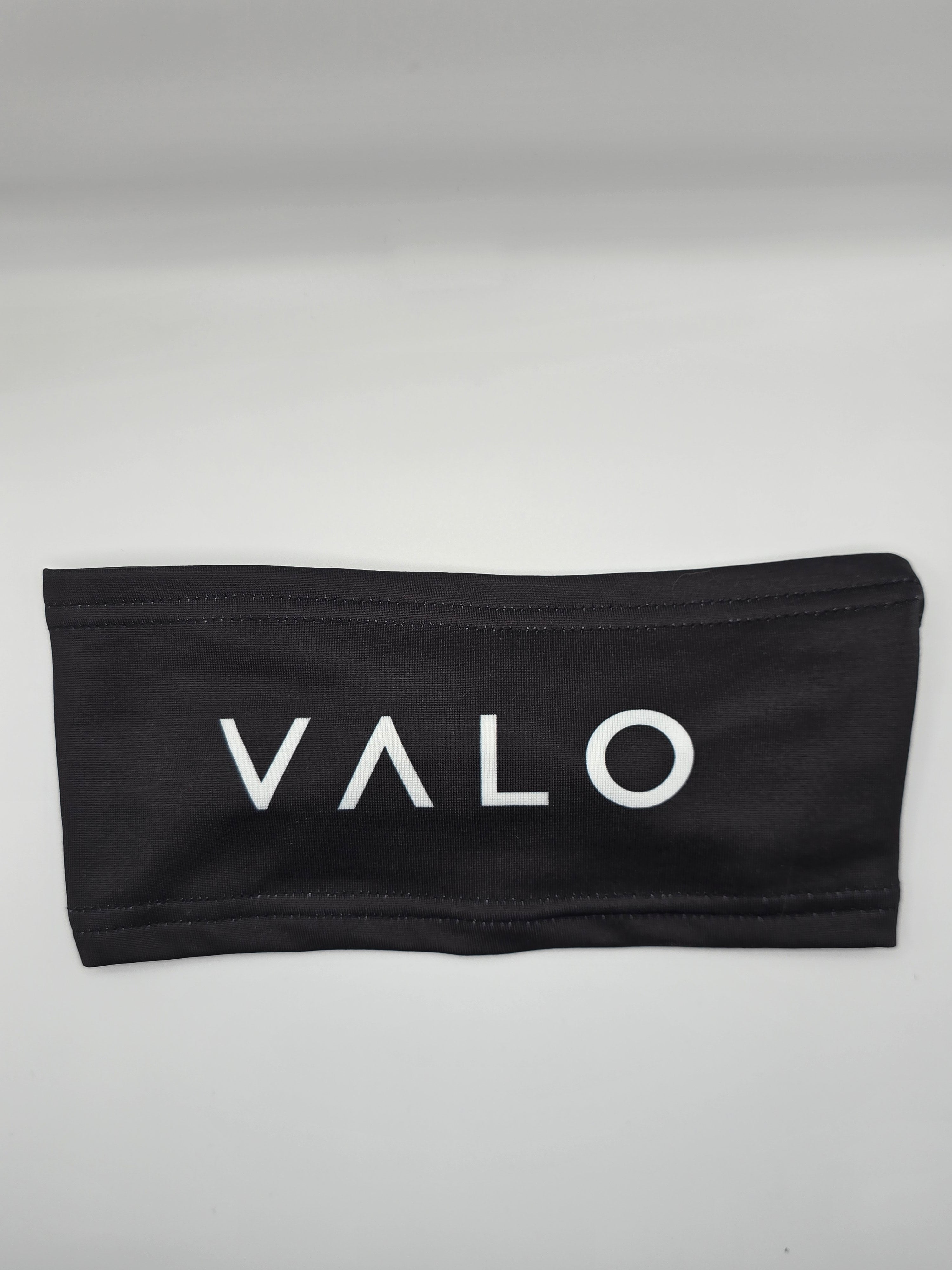 A black fabric headband with the brand name 'VALO' printed in white capital letters across the front, displayed on a neutral light gray background.