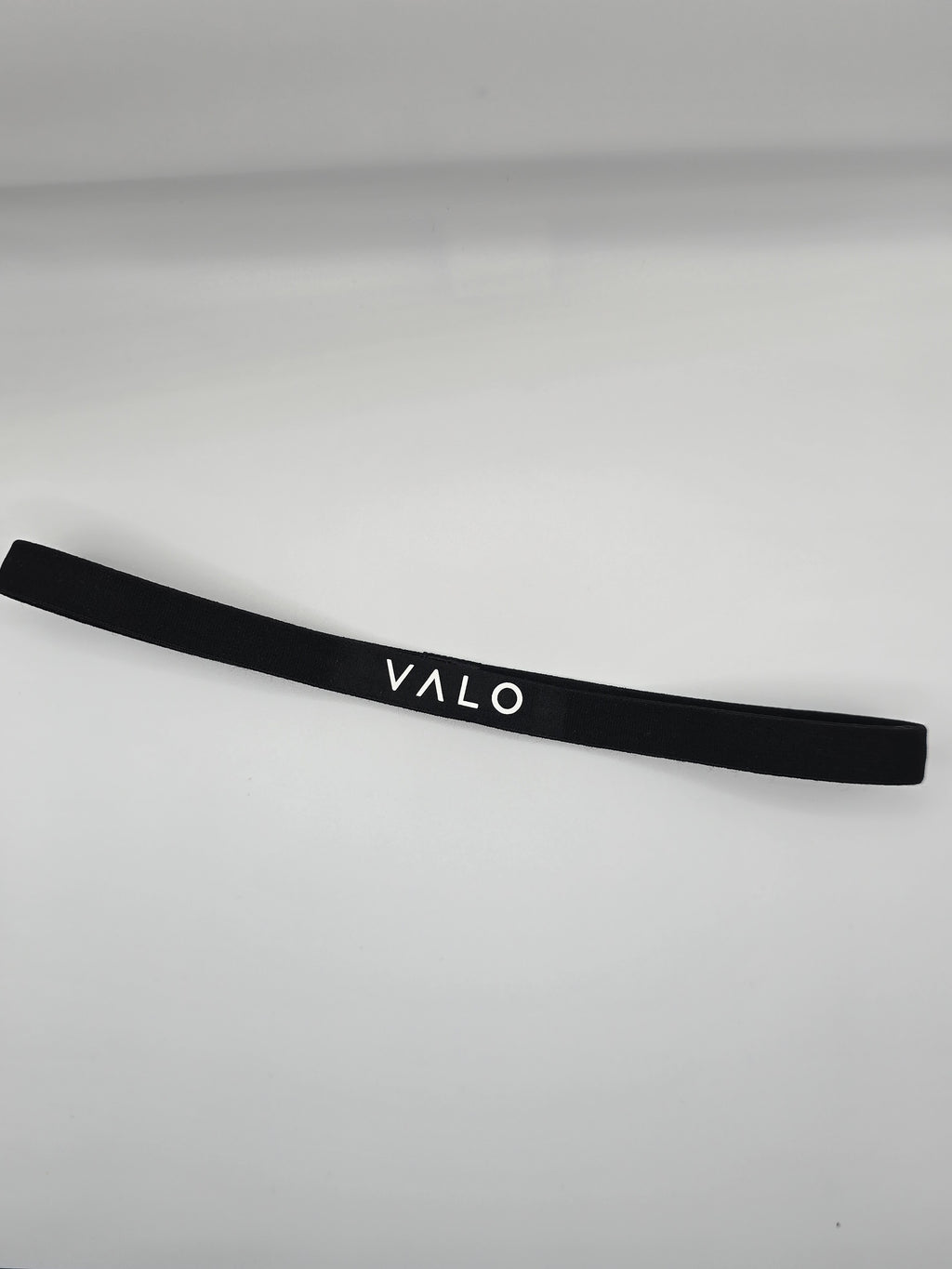 A black elastic headband with the brand name 'VALO' printed in white capital letters, displayed on a light gray background.