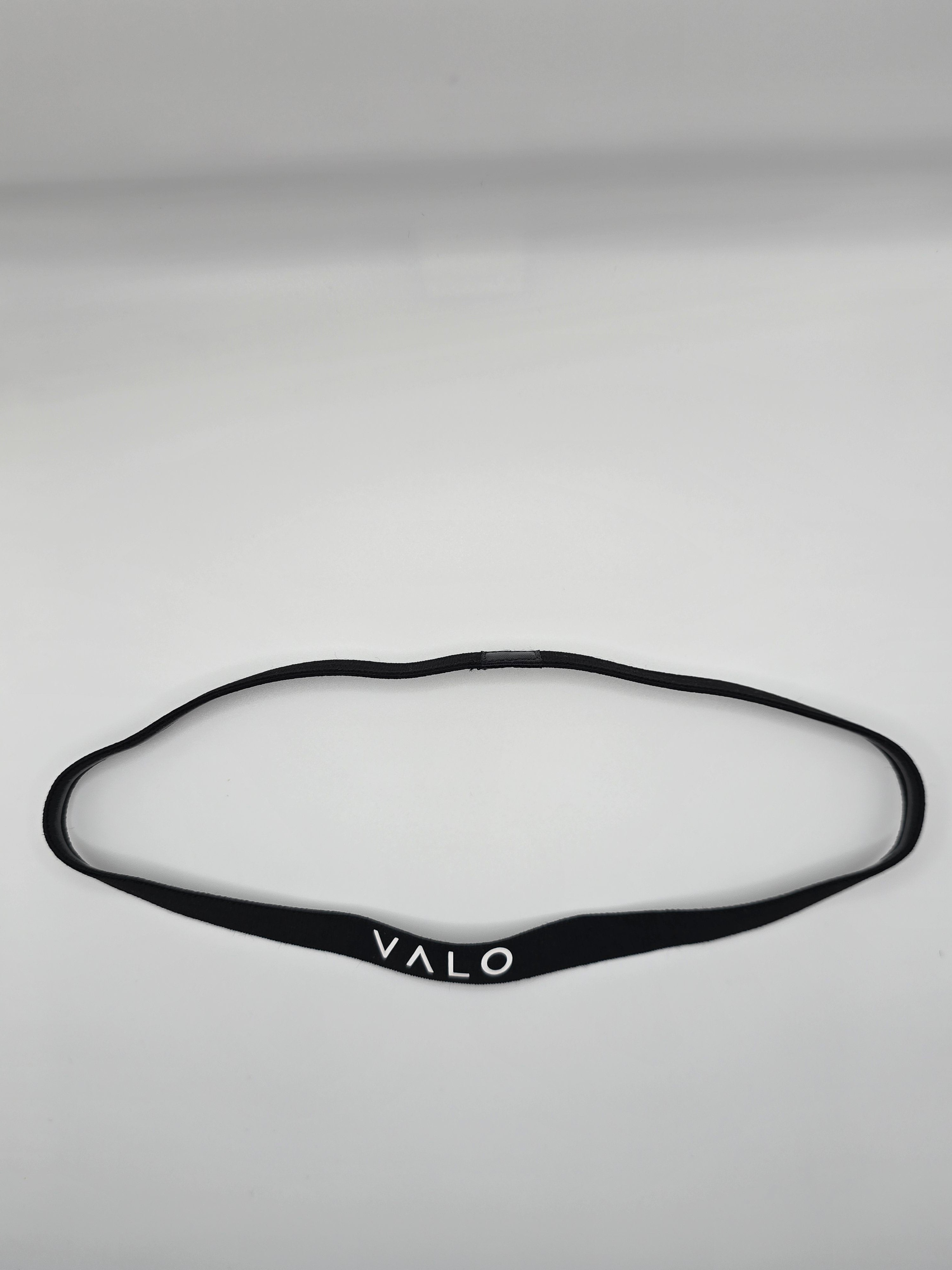 A black silicone headband with the brand name 'VALO' printed in white on the front, laid flat on a light gray background.