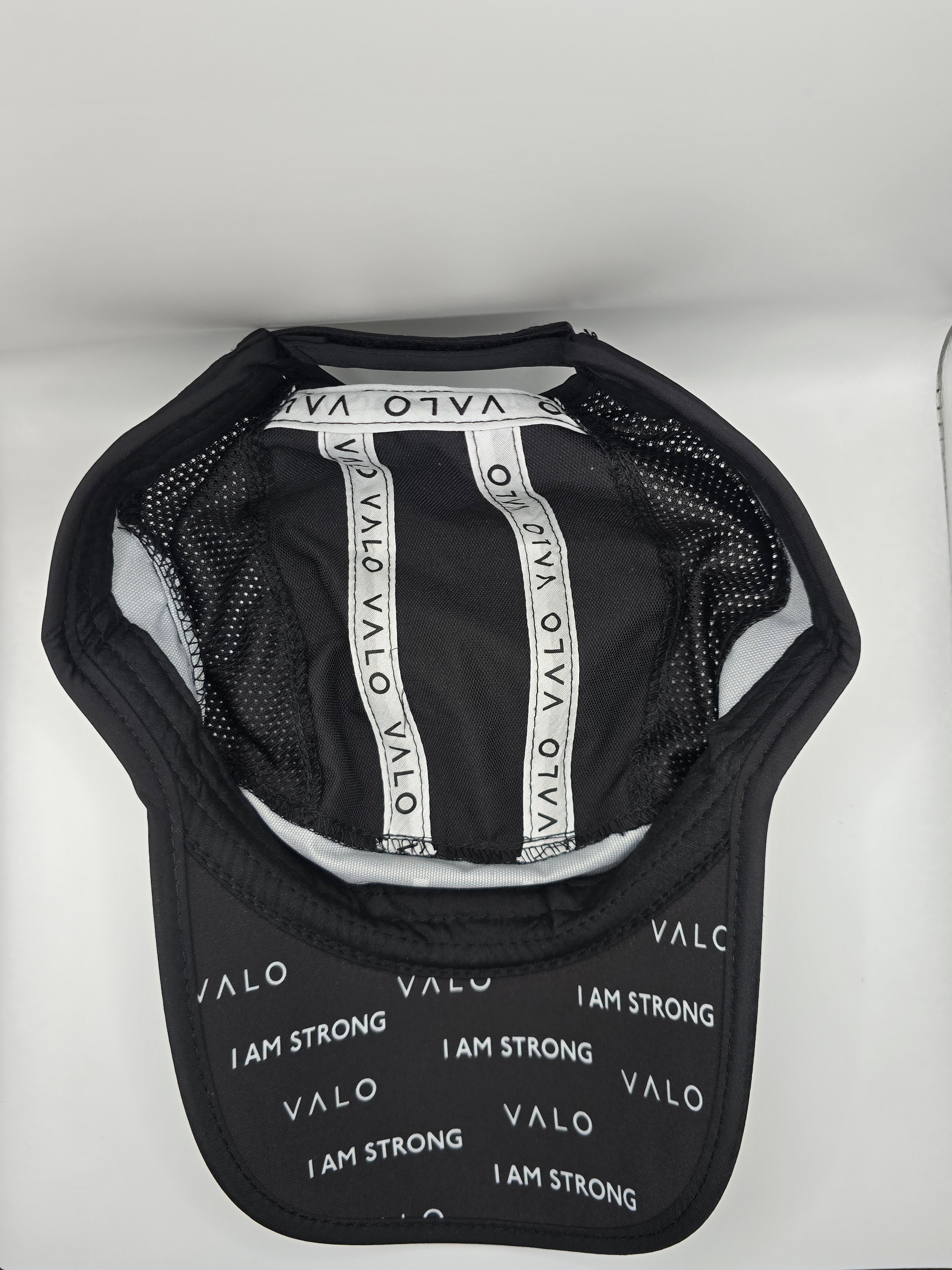 Black VALO brand baseball cap with white 'I AM STRONG' and 'VALO' text printed on the front panel and inside the crown, shown against a plain white background.